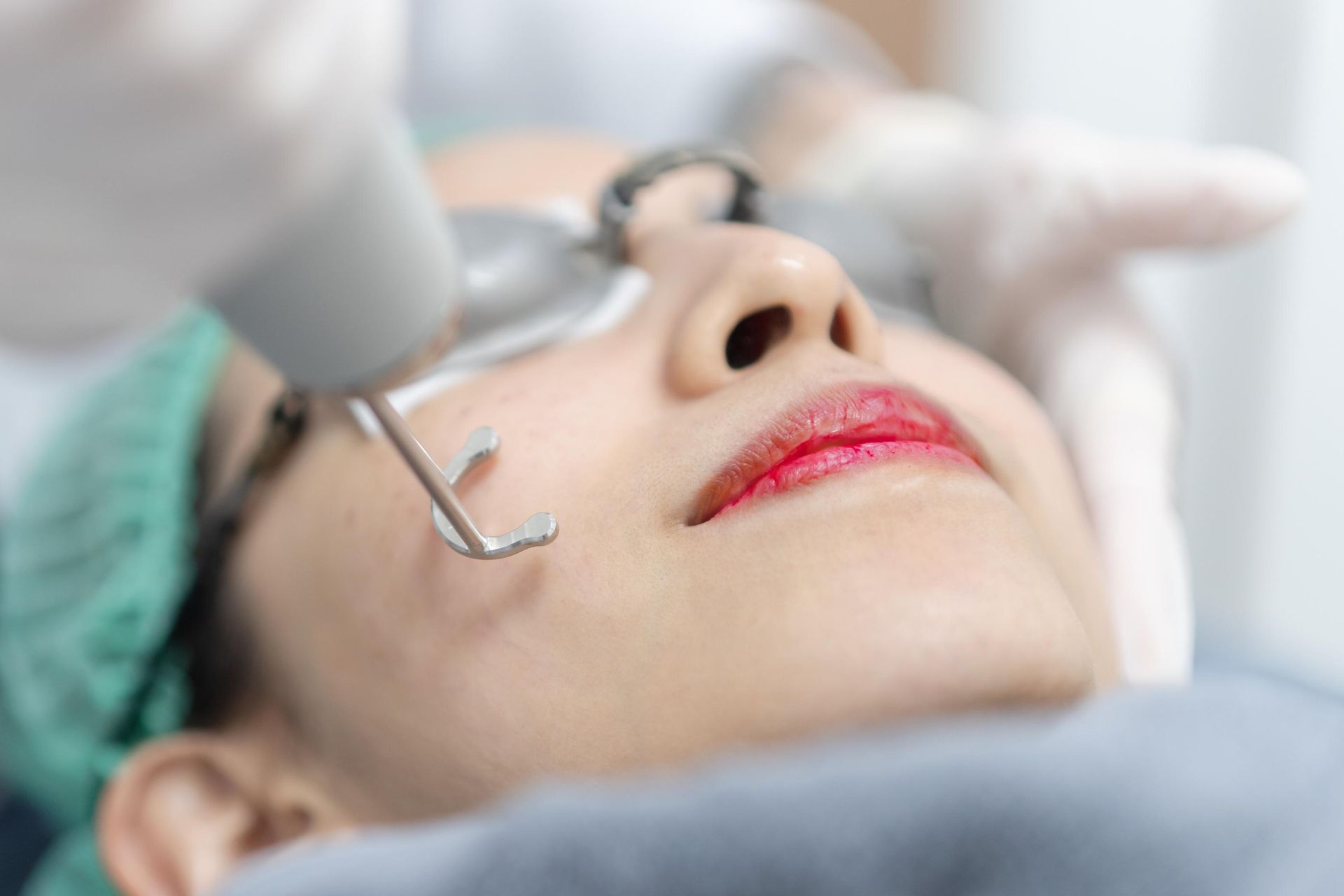 Close-up of a person receiving a dental procedure with a handheld tool near the mouth