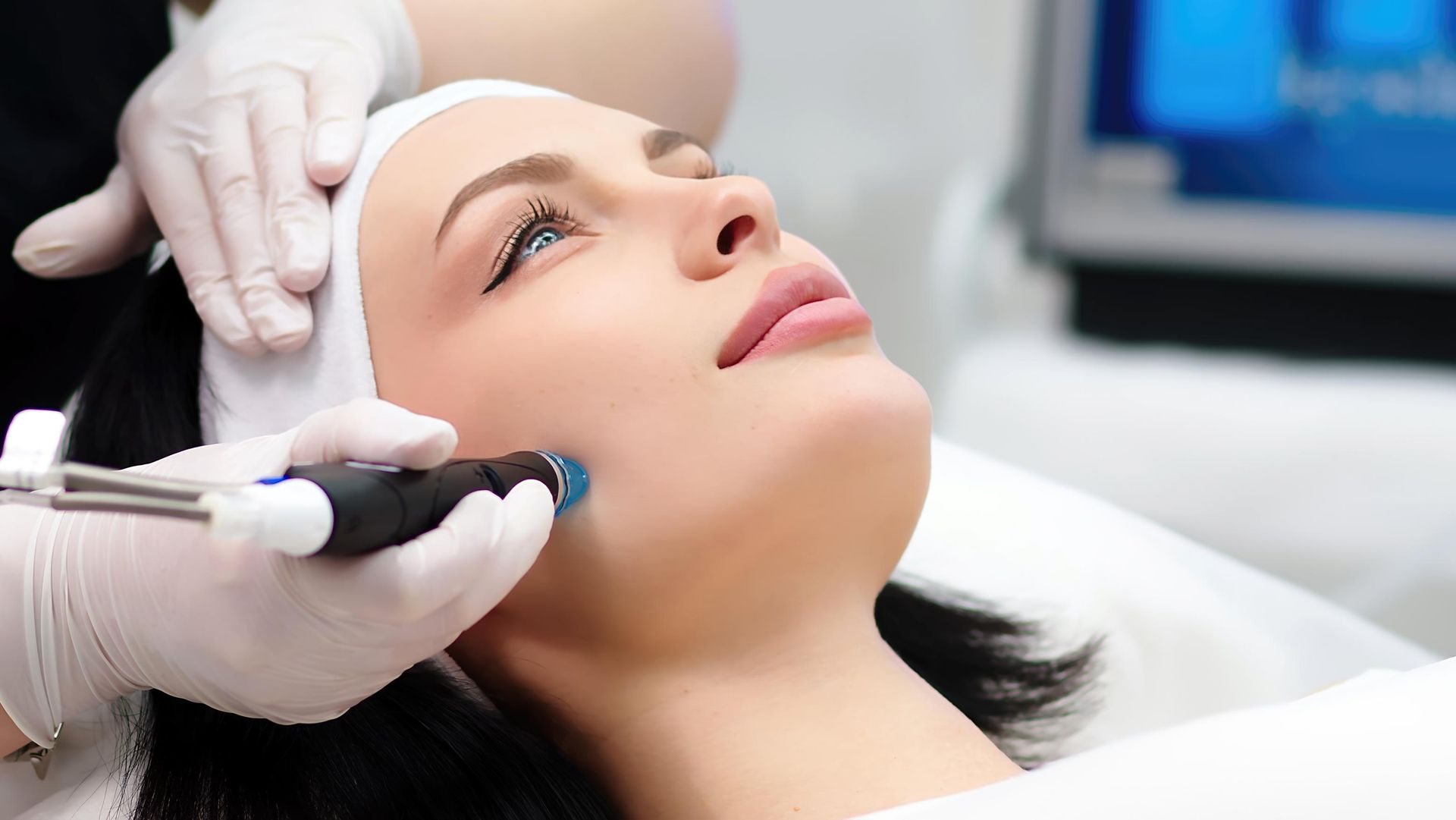 Cosmetic procedure on a woman’s face with a handheld device in a clinic