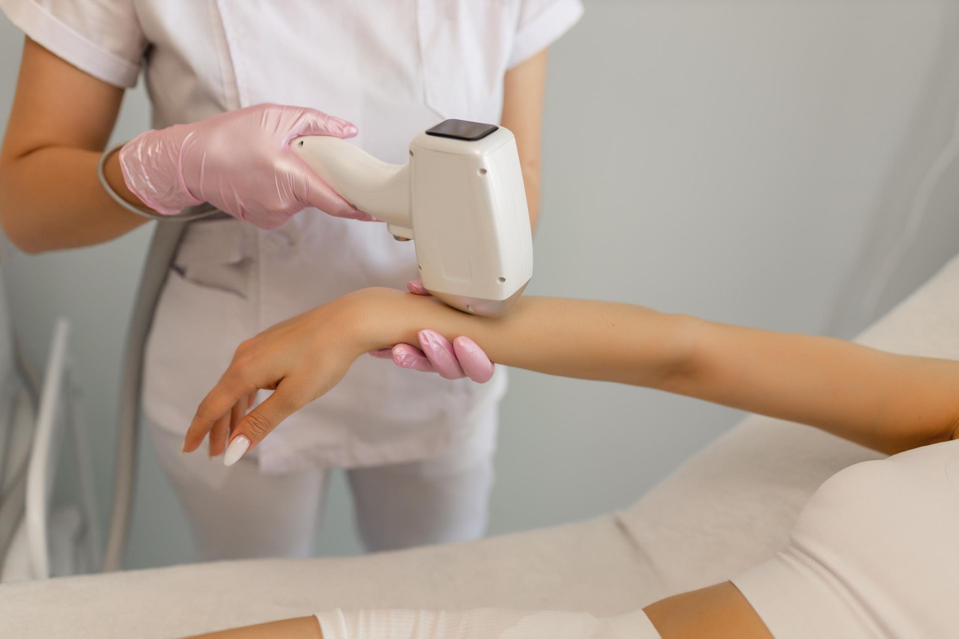 Aesthetician using a handheld device on a client’s arm during a skin treatment