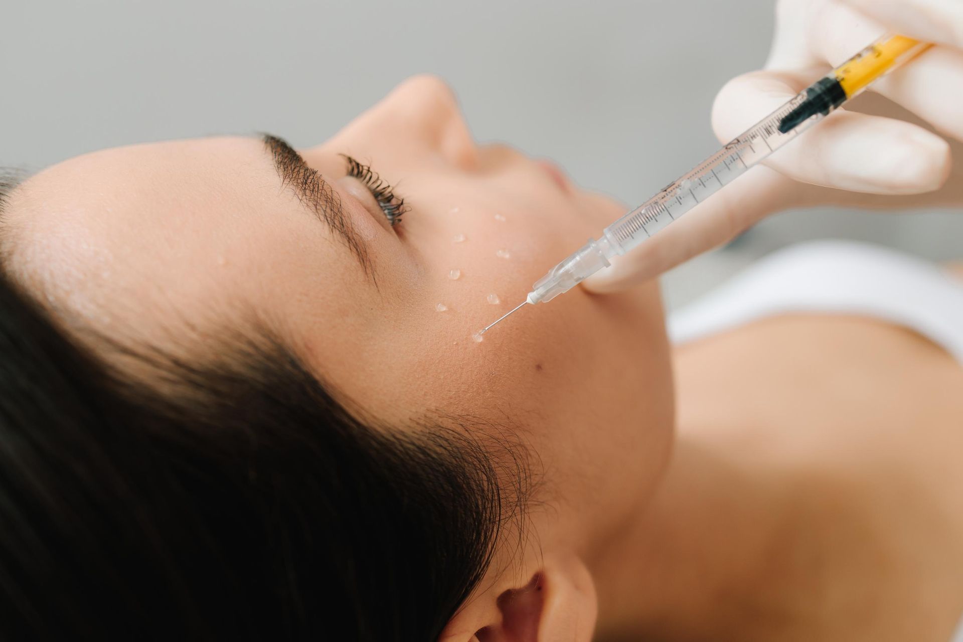 Cosmetic injection into cheek with syringe, close-up of a person lying down