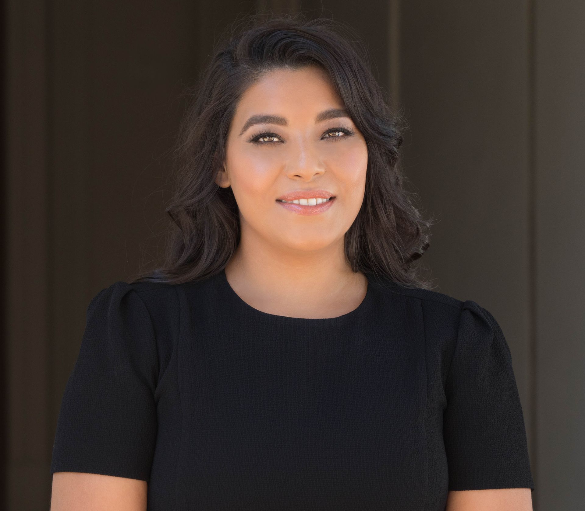 A woman in a blue tank top and necklace is smiling for the camera | Dr. Damian