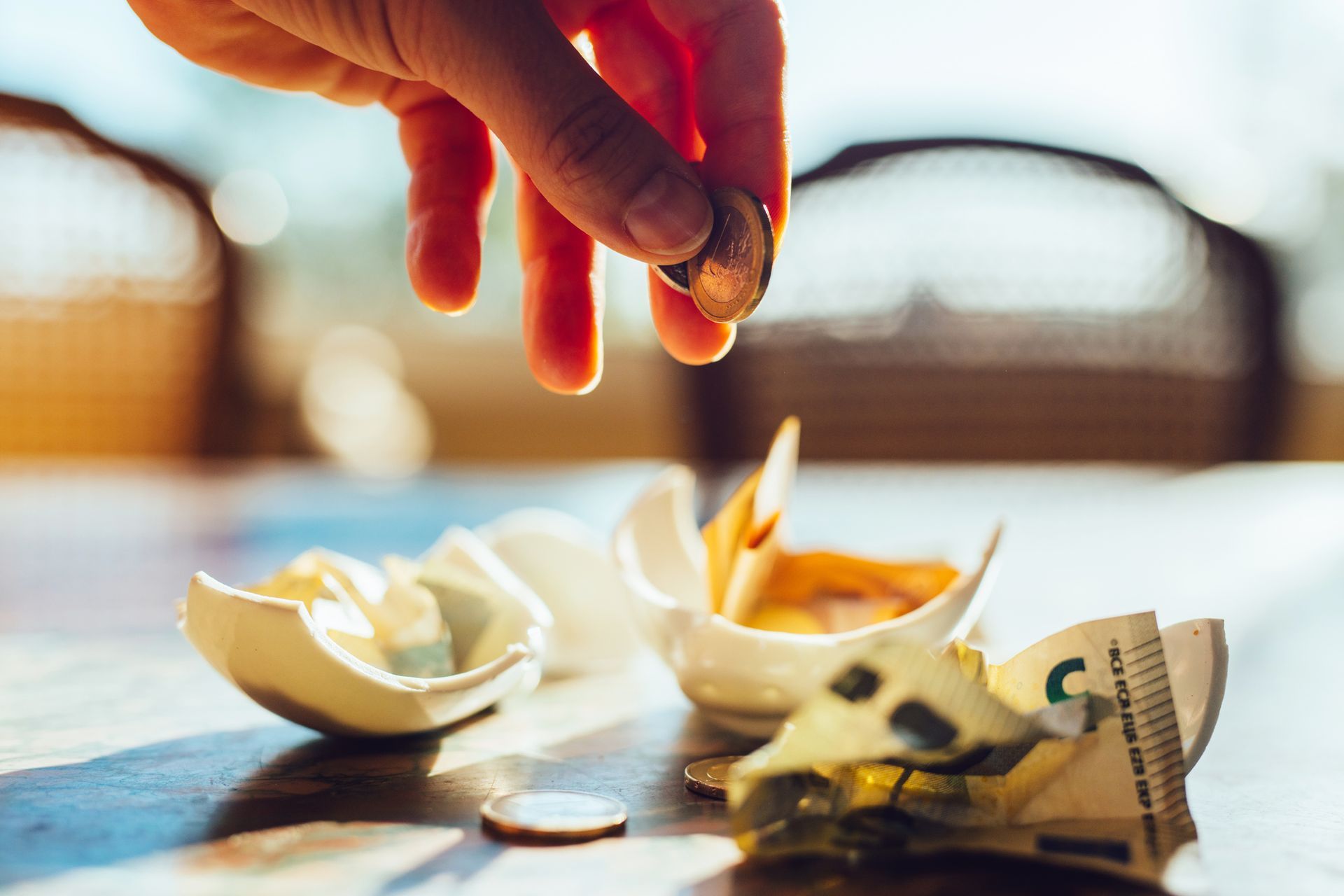 A hand counting coins from a broken piggy bank A hand counting coins from a broken piggy bank