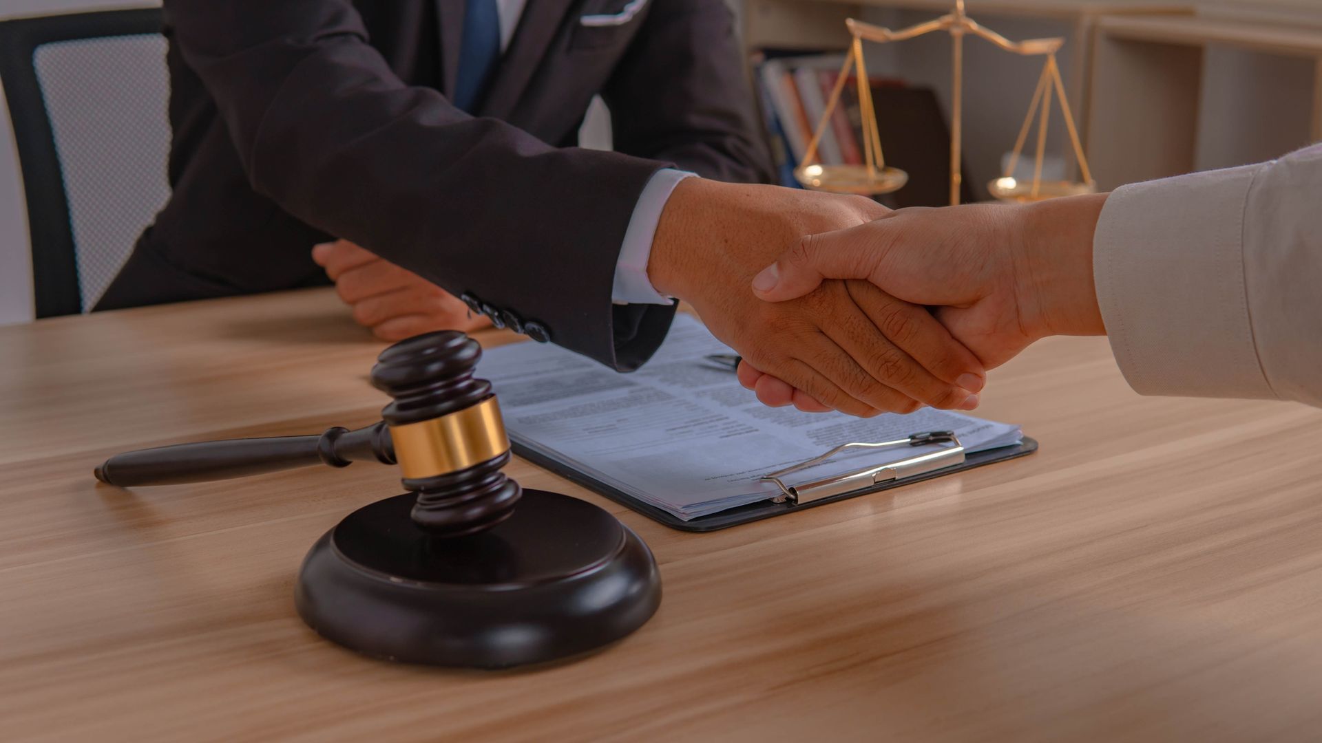 A client and her lawyer are discussing bankruptcy papers while shaking their hands.