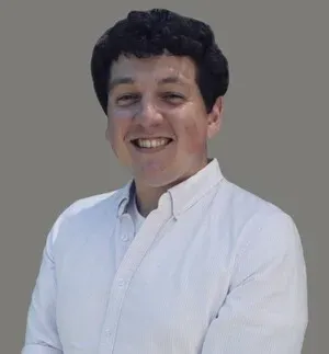 Smiling person in a white shirt against a plain gray background