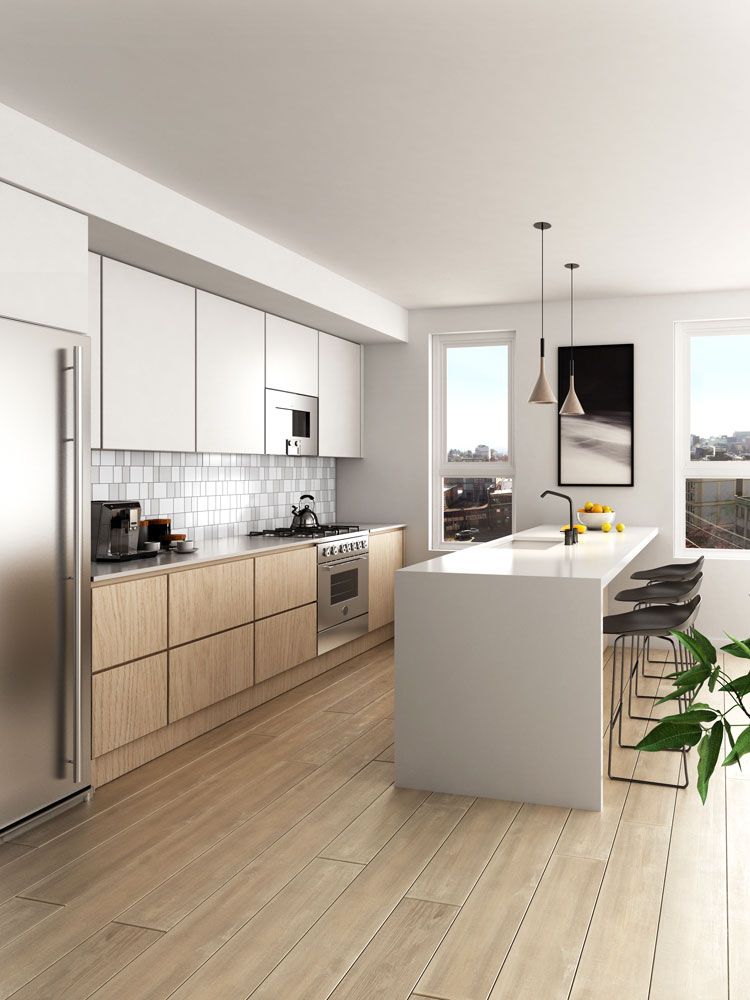 Modern white kitchen with island, light wood cabinets, stainless appliances, and large windows.