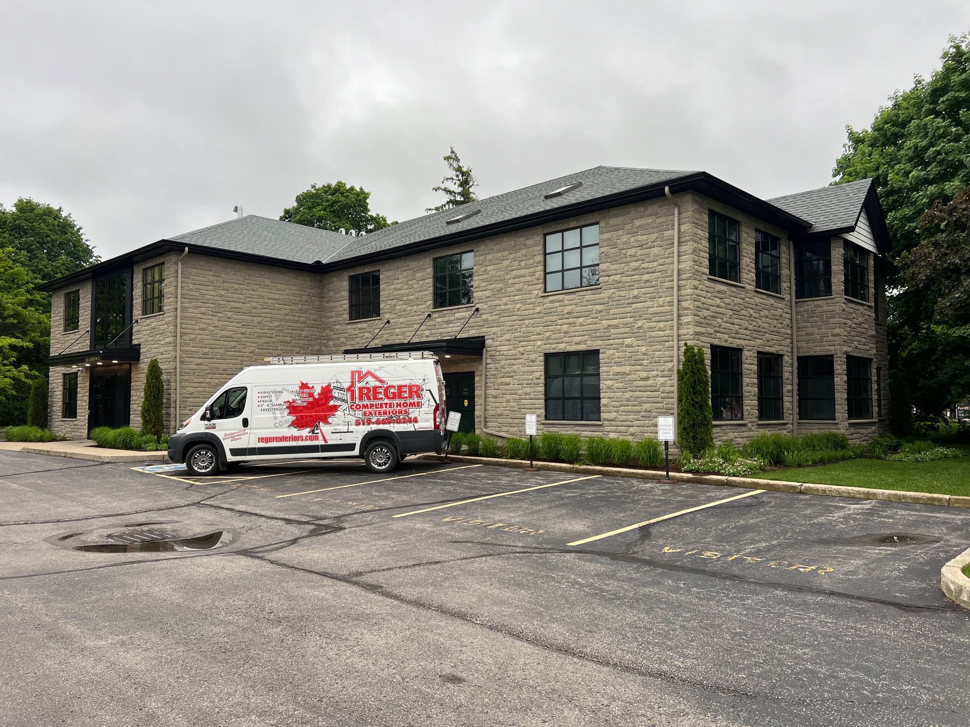 A two-story stone building with a service van parked out front on a cloudy day.