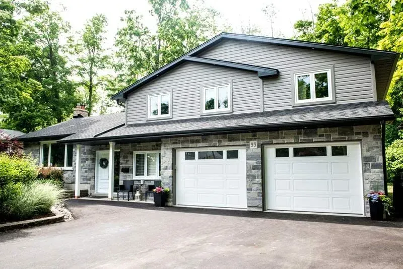 A large house with three garage doors and a driveway.