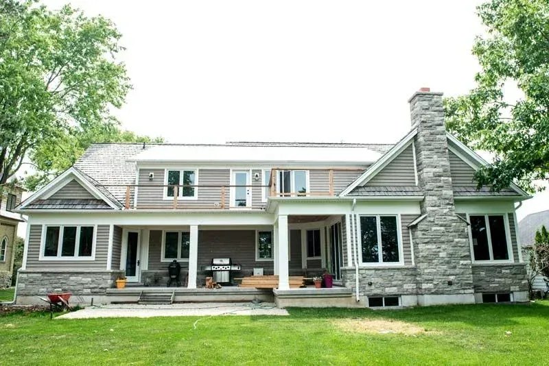 A large house with a lot of windows and a stone chimney