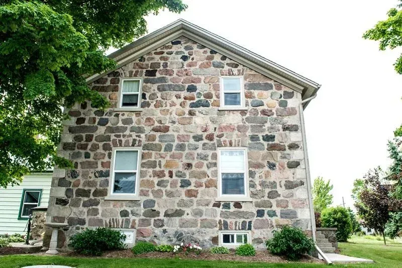 A large stone house with white windows and a roof