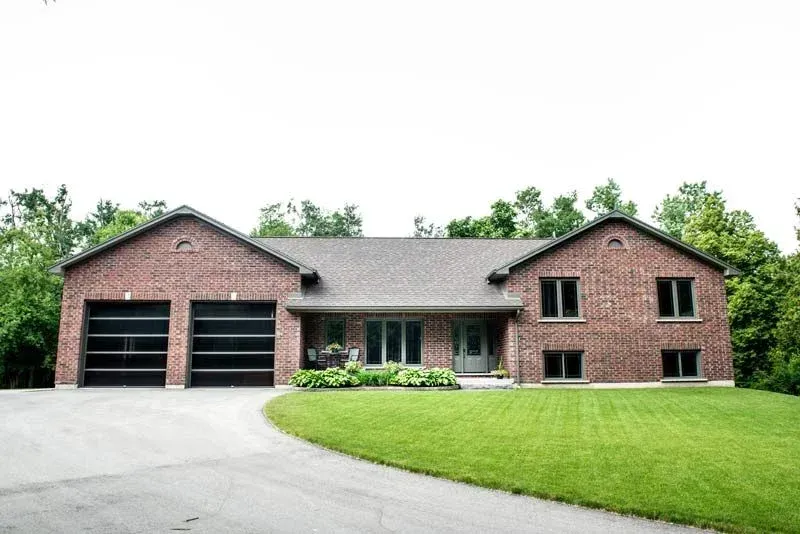 A large brick house with two garage doors and a driveway