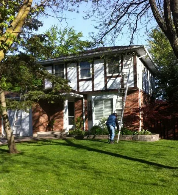 A man standing in front of a house with a ladder