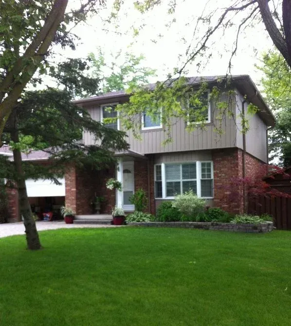 A brick house with a lush green lawn in front of it