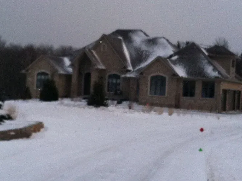 A large house with snow on the roof is surrounded by snow