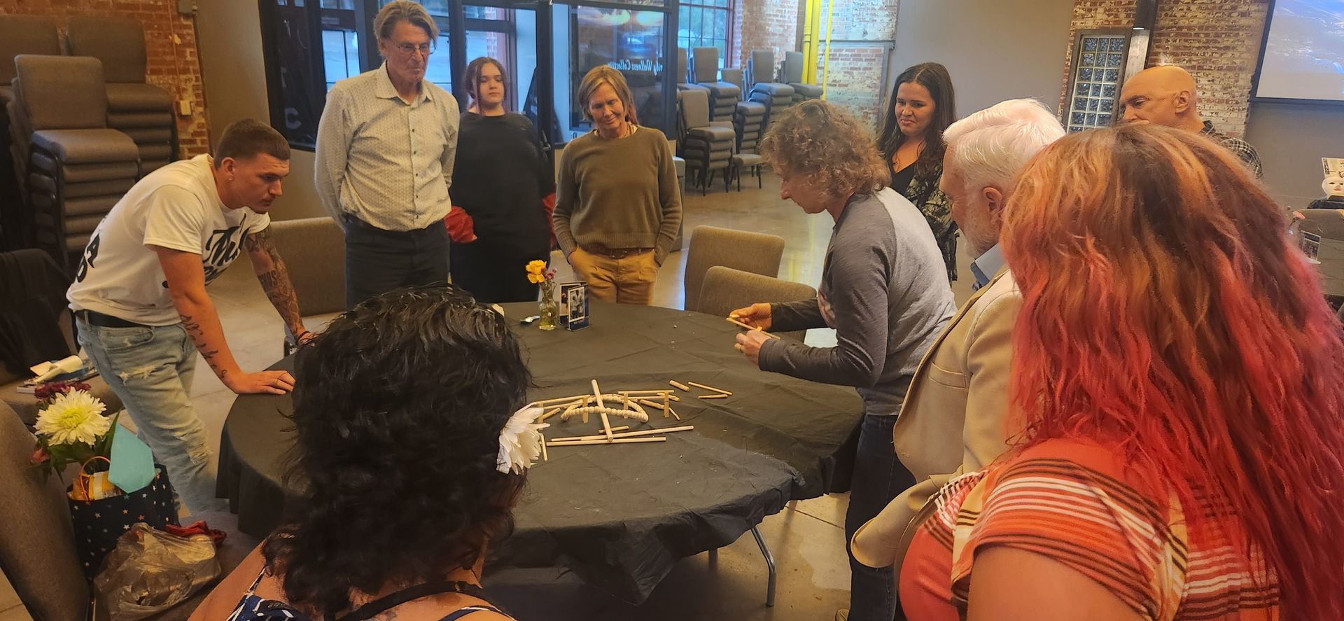 People gathered around a table, working on a craft project in a cozy indoor room.