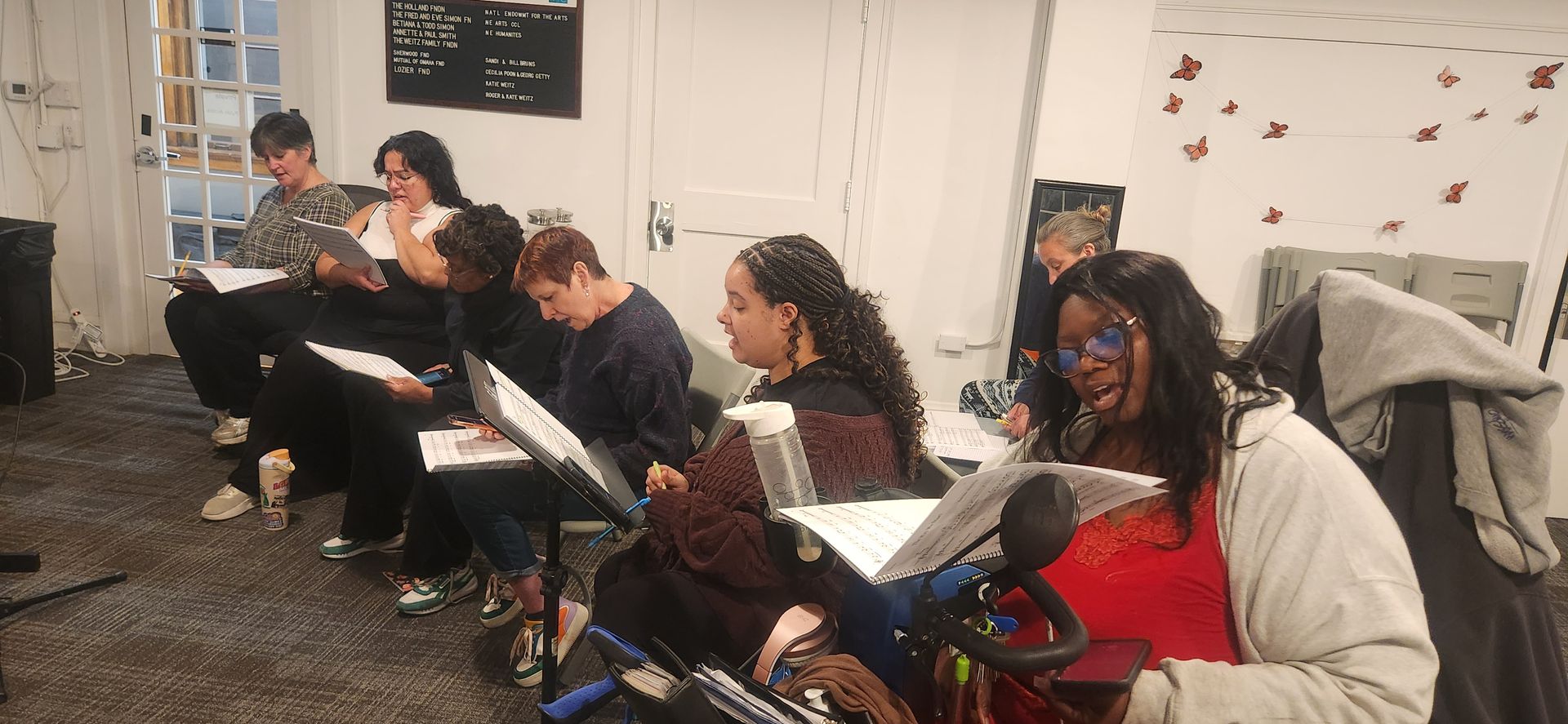 People seated in a classroom, reading and taking notes during a group discussion.