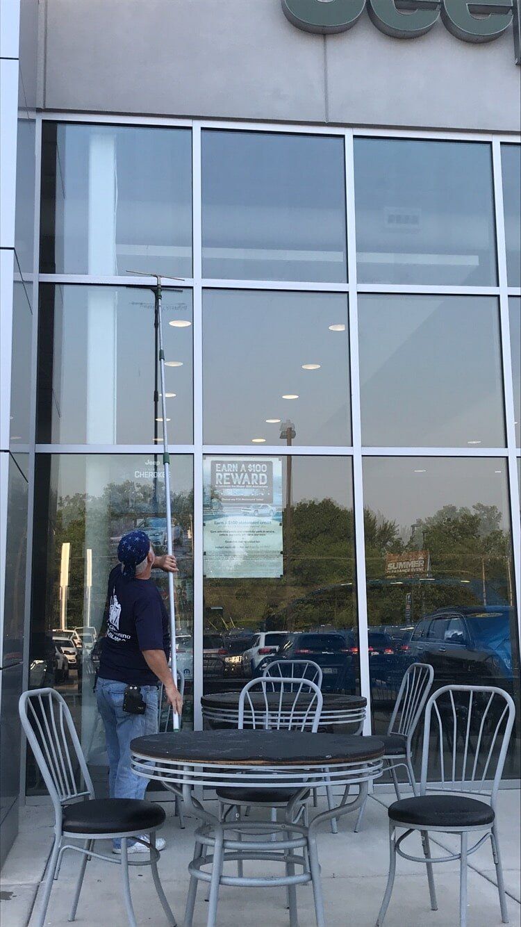Soft Washing — Man Cleaning the Front Window in Crown Point, IN