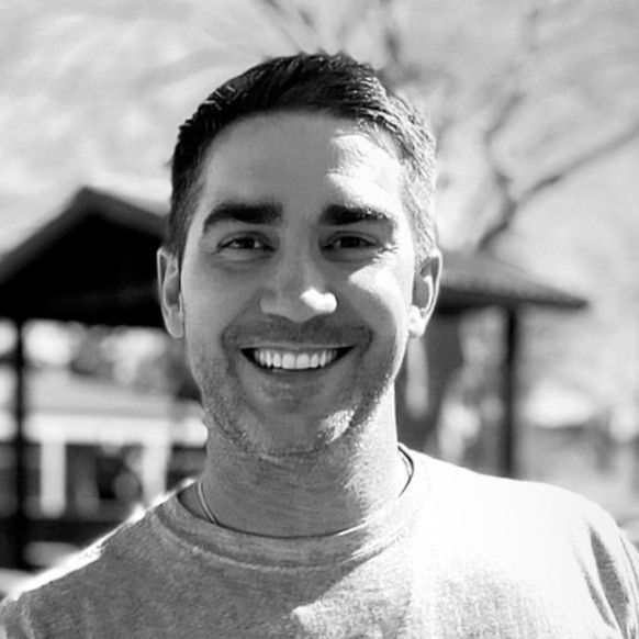 A man with a beard is smiling in a black and white photo.