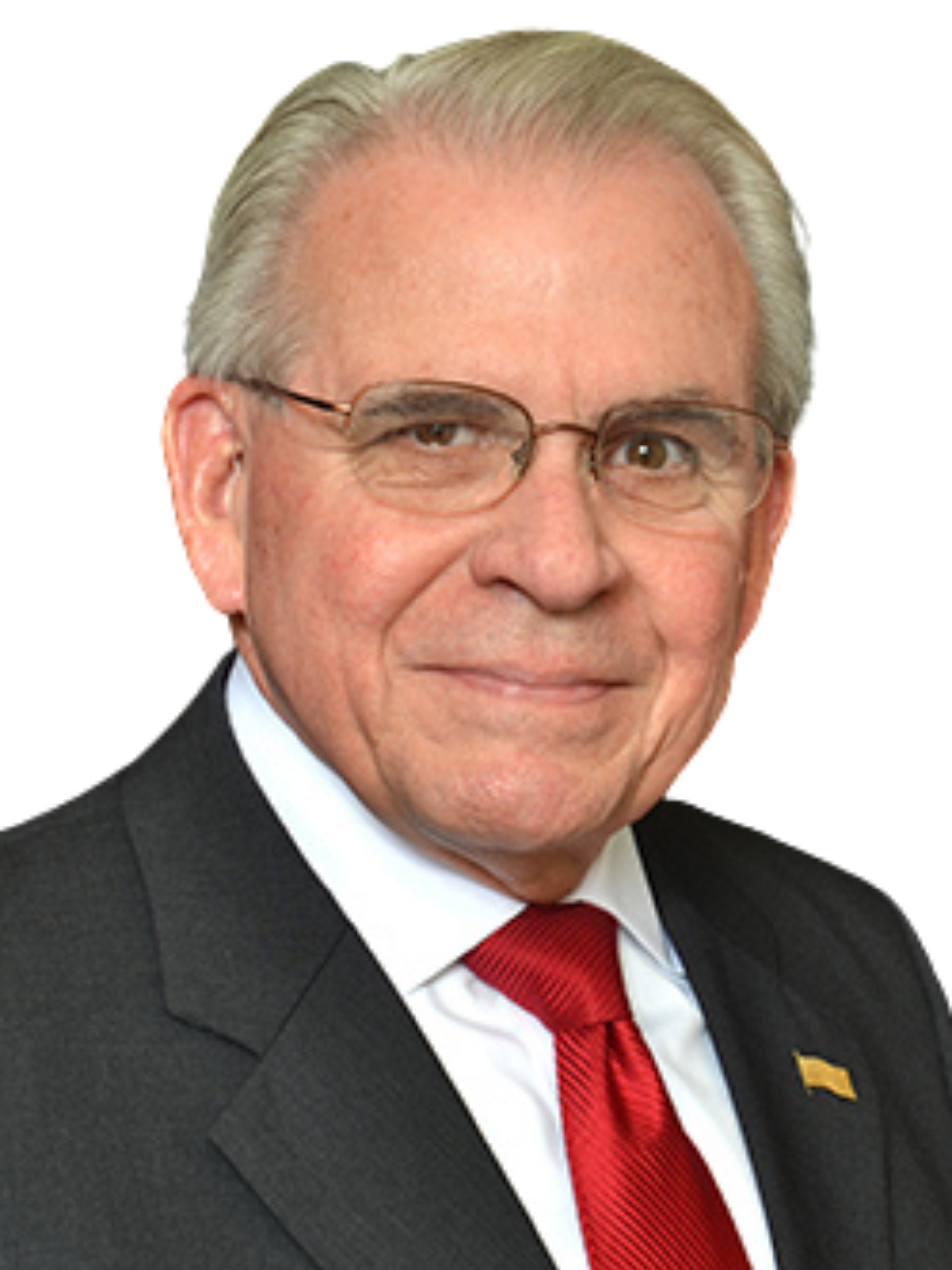 Older man in suit and tie, wearing glasses, smiling.