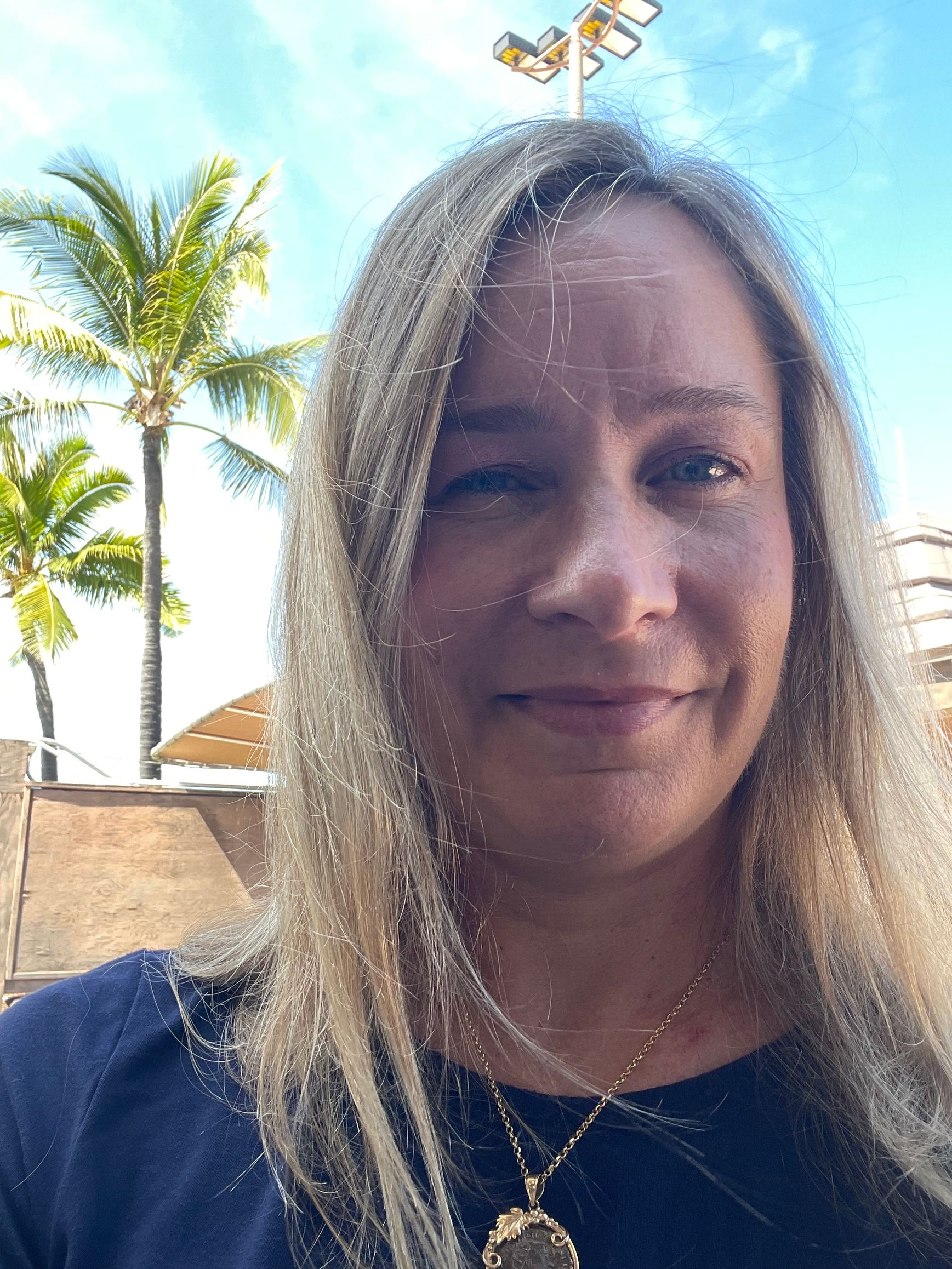 Scuba diver with arms raised, underwater, smiling, wearing black wetsuit and equipment. Blue water background.
