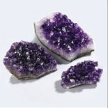 Three amethyst crystal clusters in varying sizes, displaying purple hues.