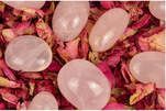 Pink rose quartz stones on rose petals.