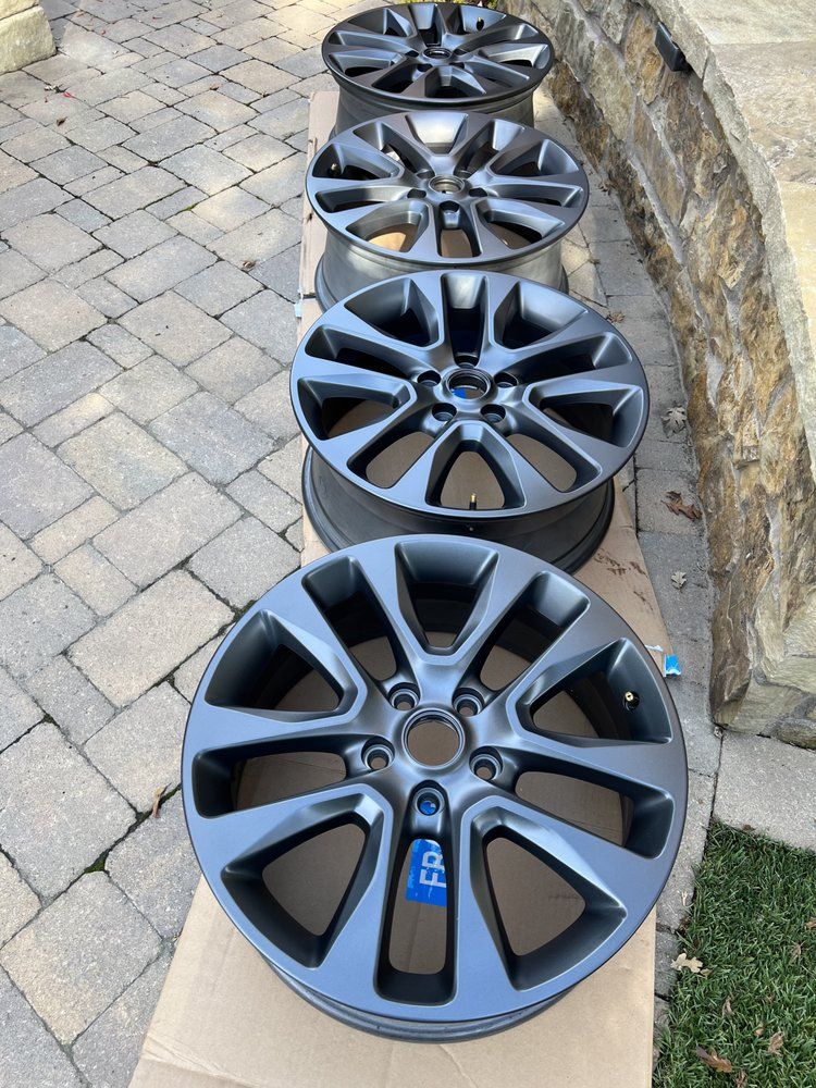A row of black wheels are lined up on a brick sidewalk.
