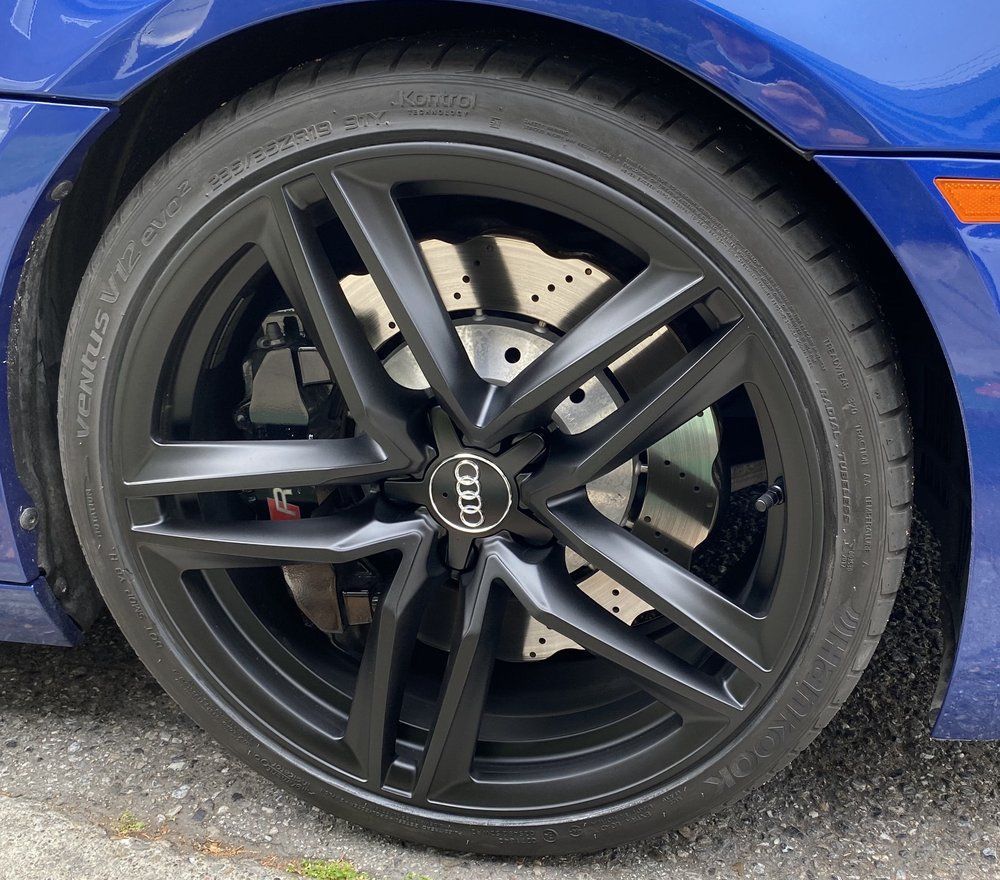 A close up of a blue car with black wheels and tires