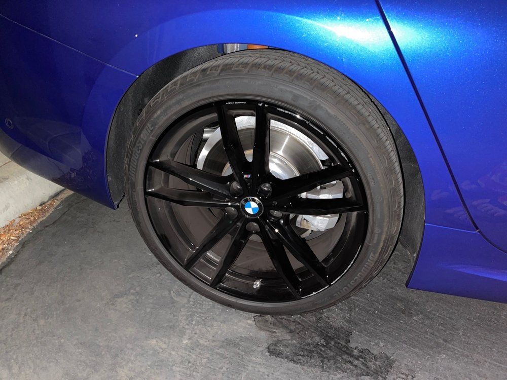 A blue bmw with black wheels and tires is parked in a garage.