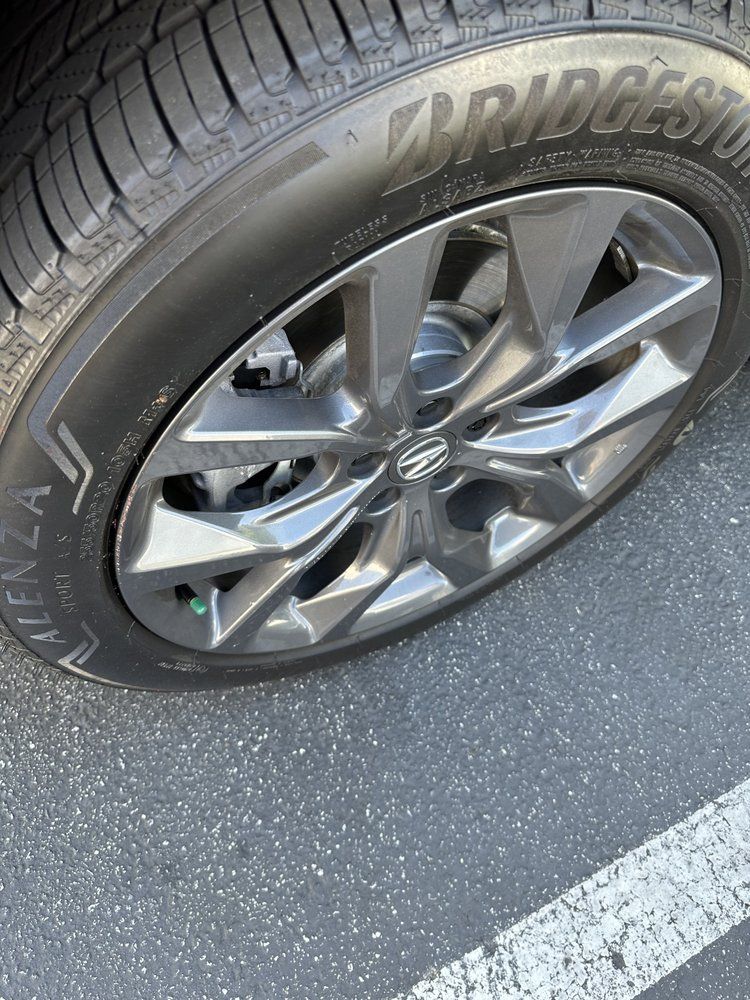A close up of a tire on a car in a parking lot.