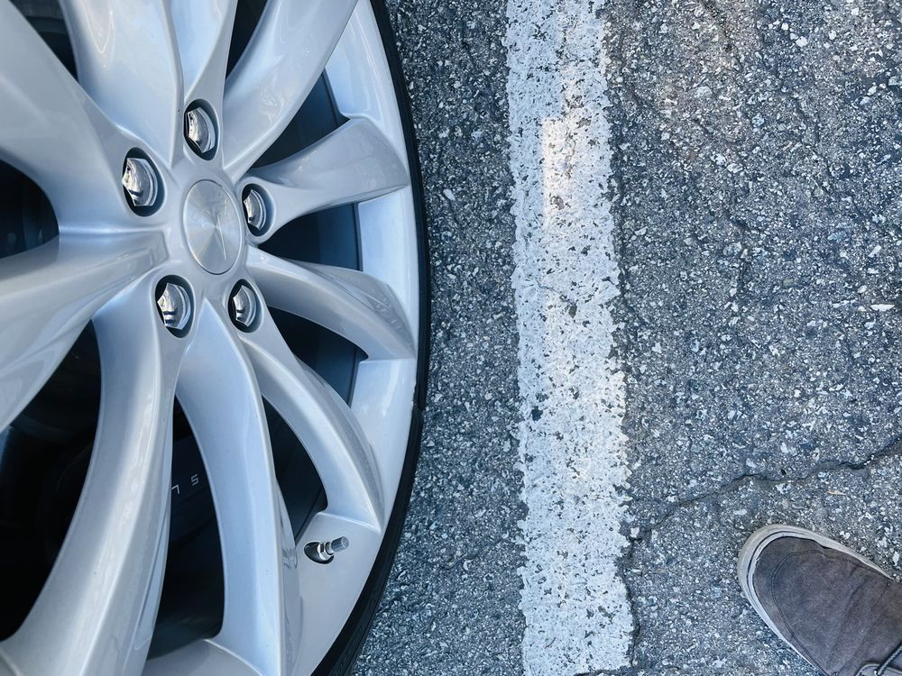 A person standing next to a silver car wheel