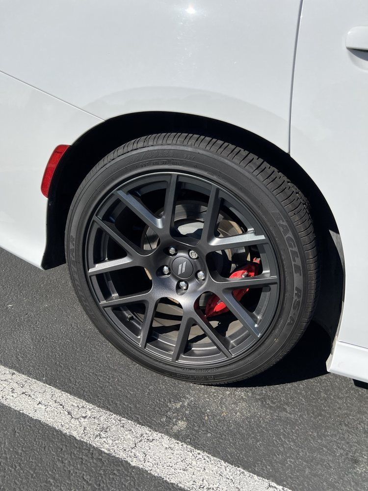 A close up of a car wheel in a parking lot.