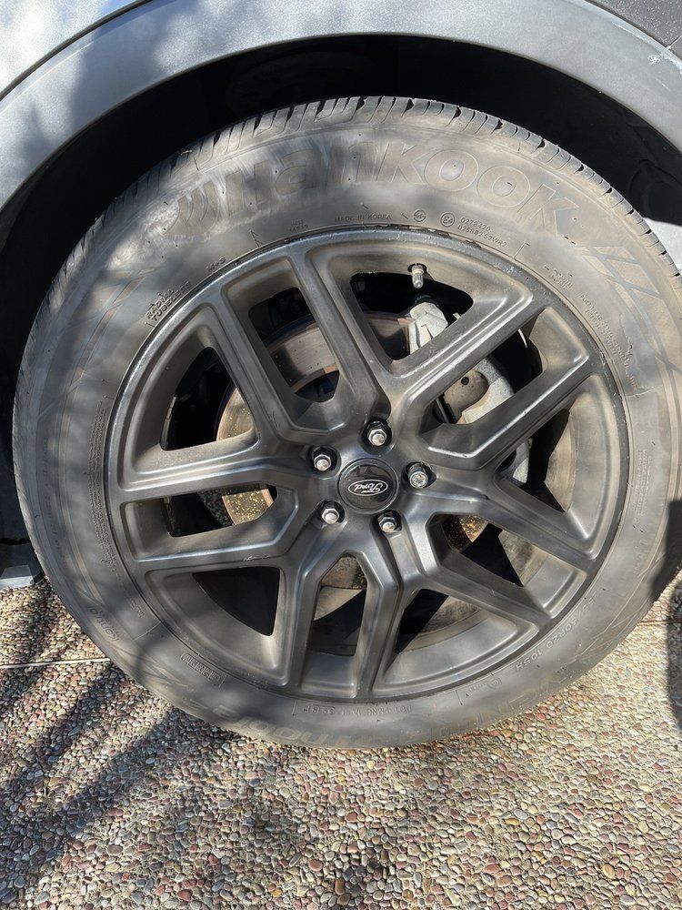 A close up of a car wheel on a gravel road.