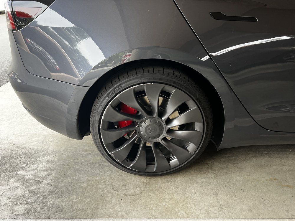A tesla model 3 is parked in a garage.