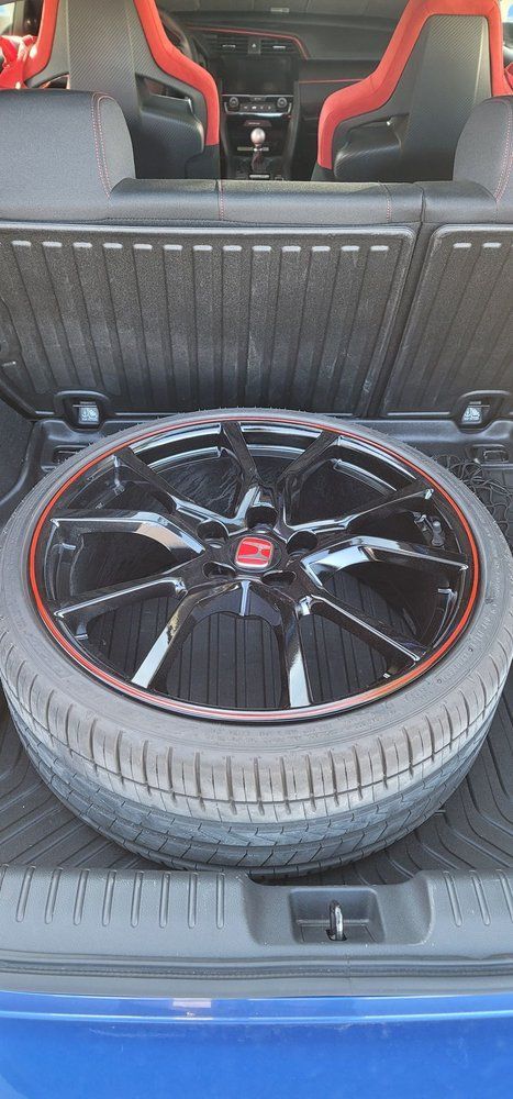 A spare tire is sitting in the trunk of a blue car.