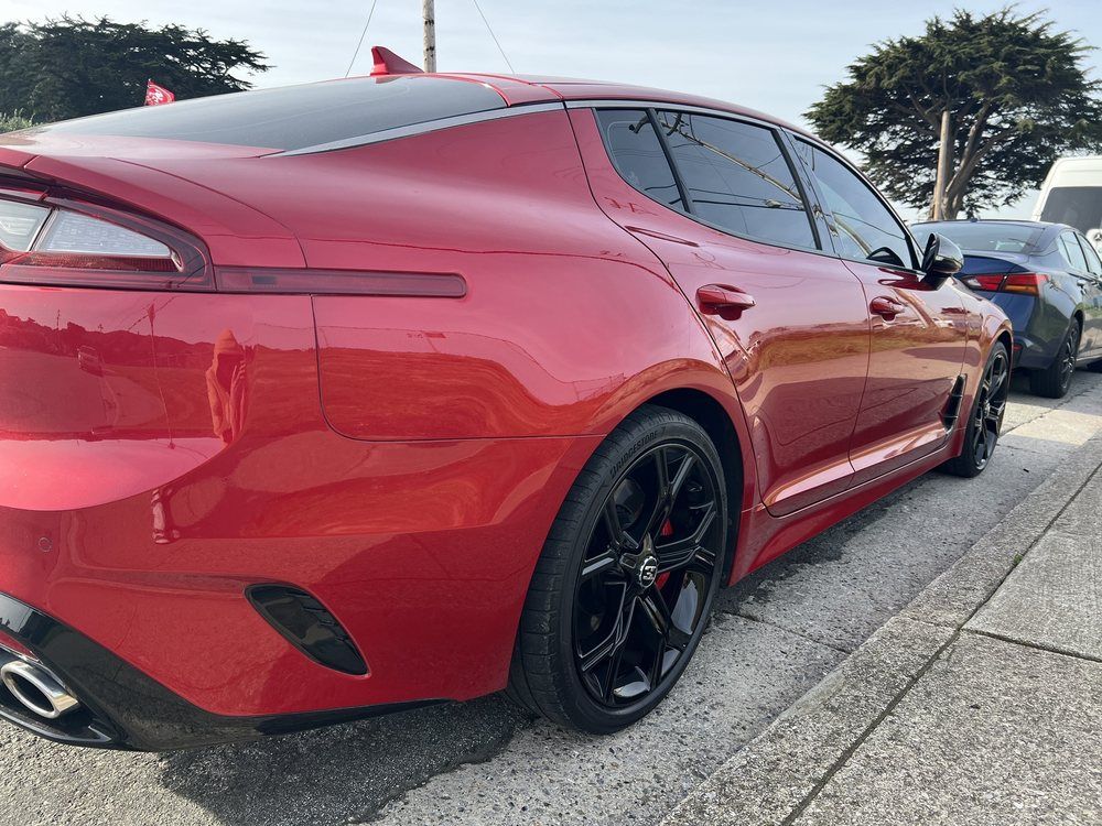 A red car is parked on the side of the road.