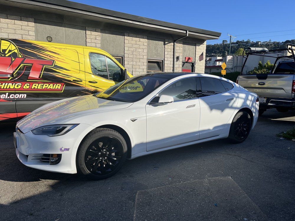 A white tesla model s is parked in front of a building.
