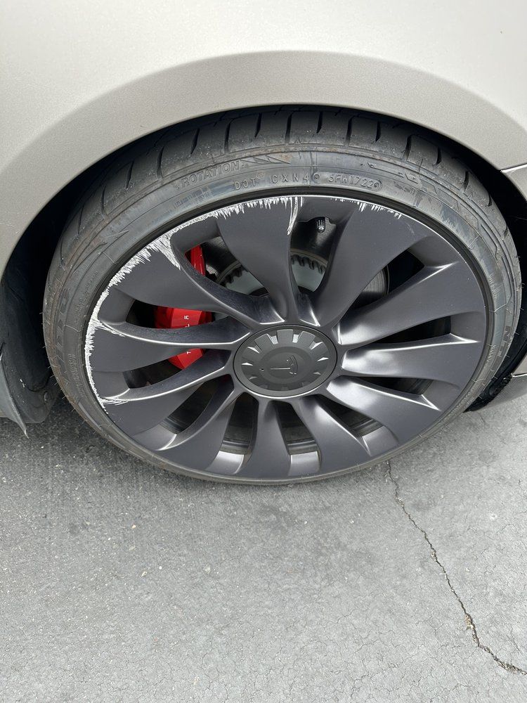 A close up of a tesla model 3 wheel with red brake calipers.