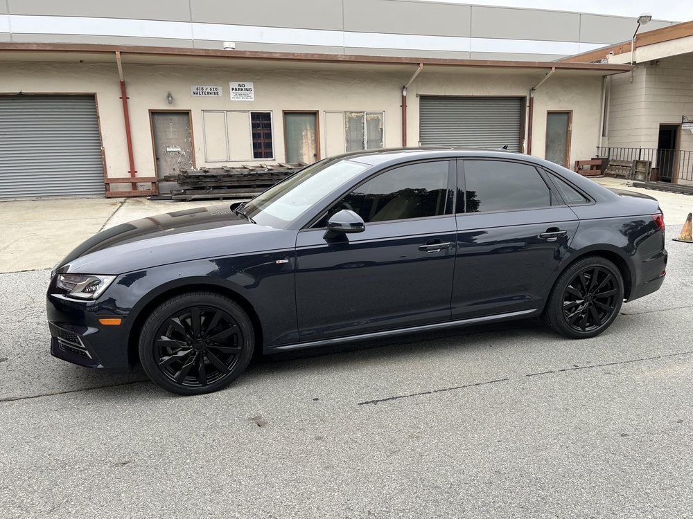 A black audi a4 is parked in front of a building.