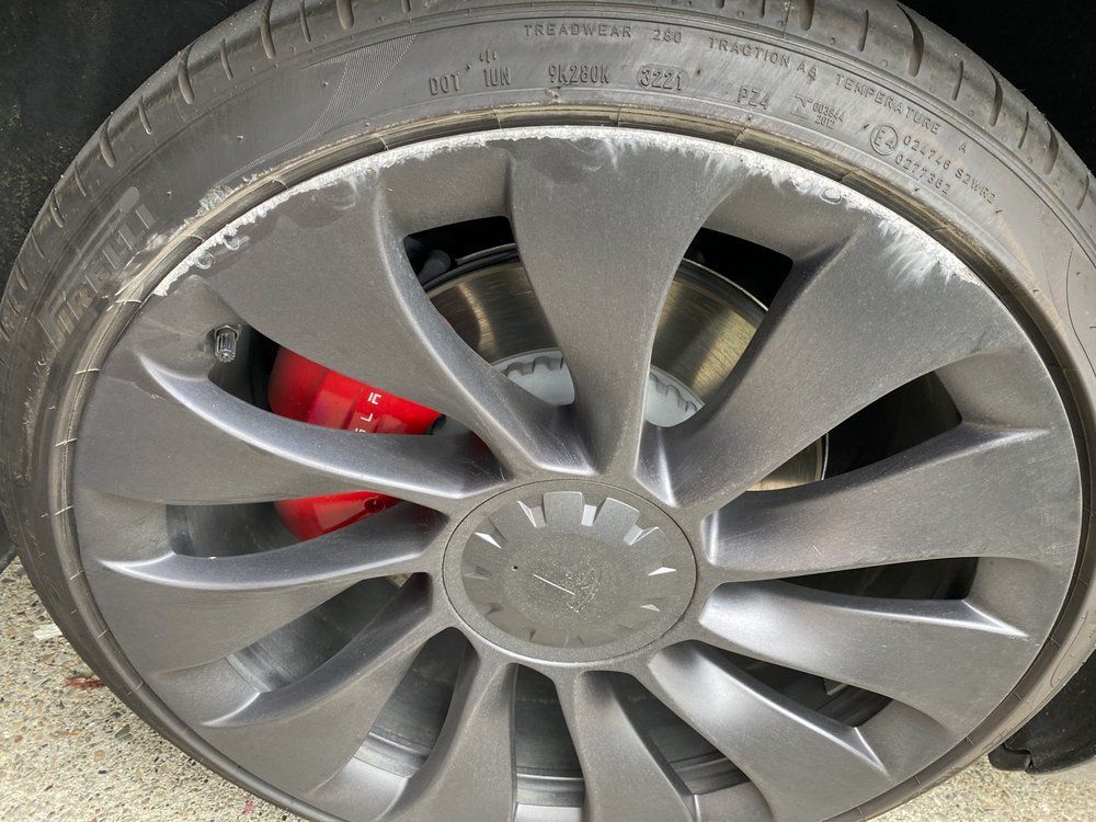 A close up of a tesla wheel with red brake calipers