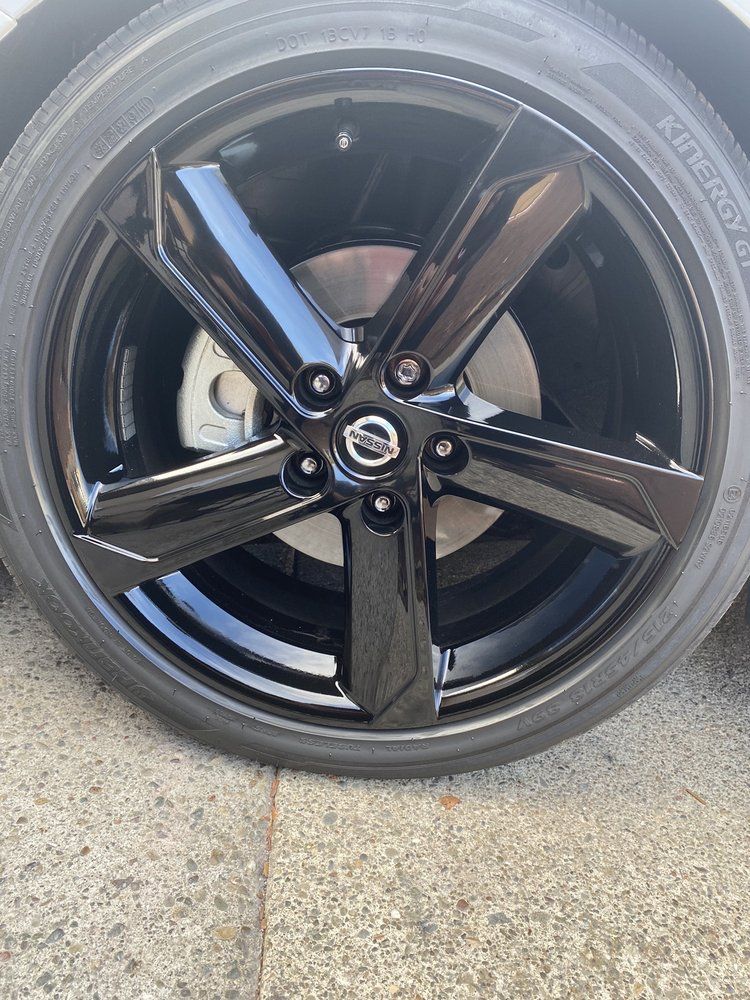A close up of a black car wheel on a sidewalk.