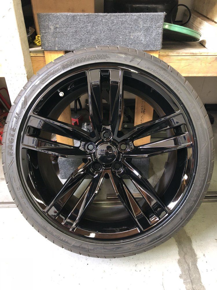 A black tire is sitting on top of a black wheel.