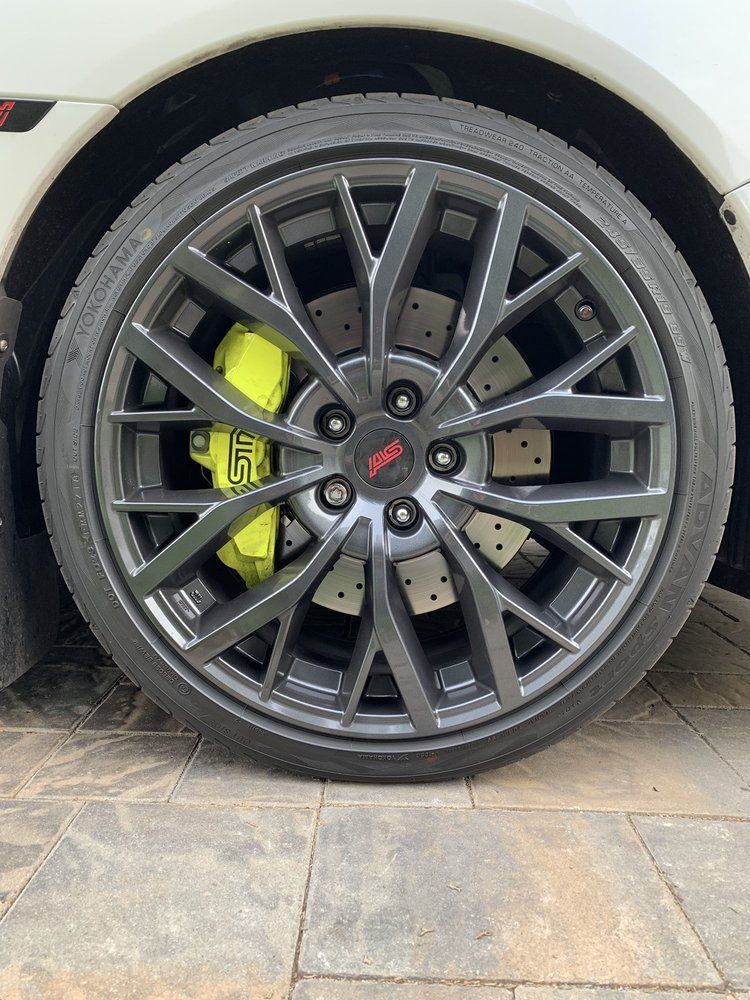 A close up of a car wheel with a yellow brake caliper.