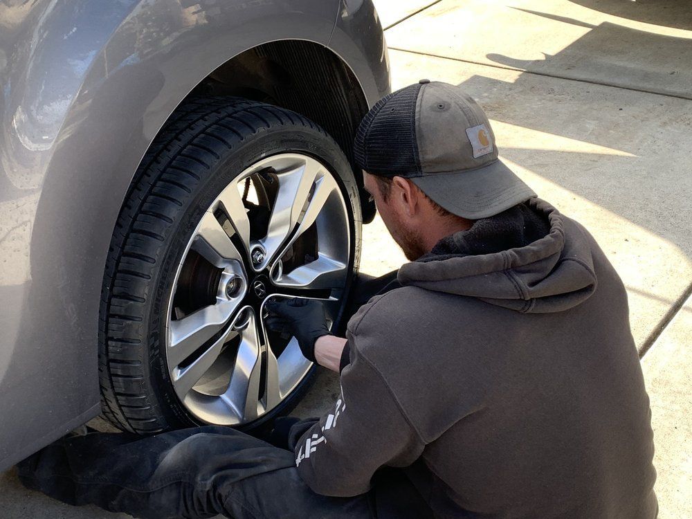 A man is changing a tire on a car in a driveway.