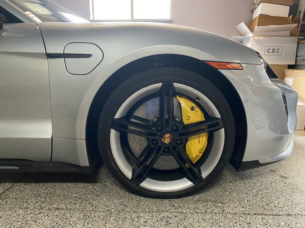 A silver porsche taycan is parked in a garage.