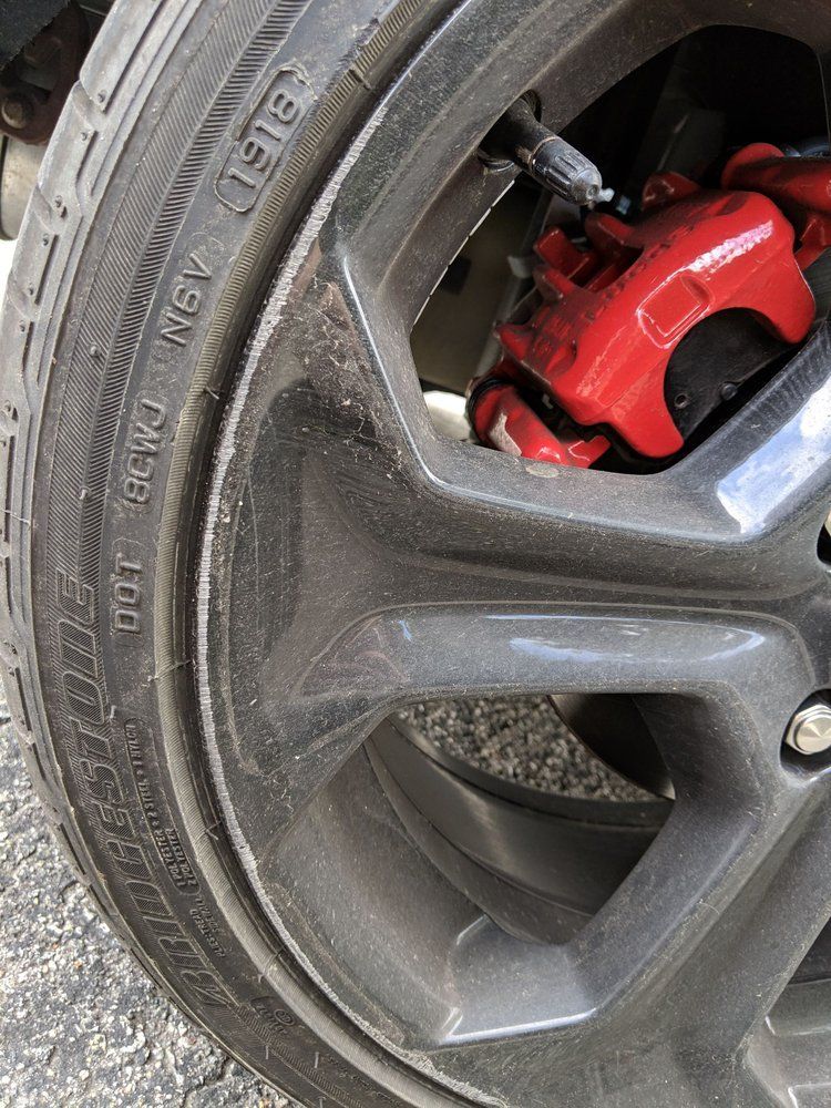 A close up of a tire on a car with a red brake caliper.