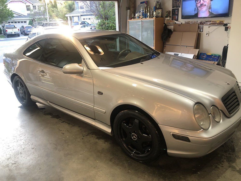 A silver mercedes benz coupe is parked in a garage.