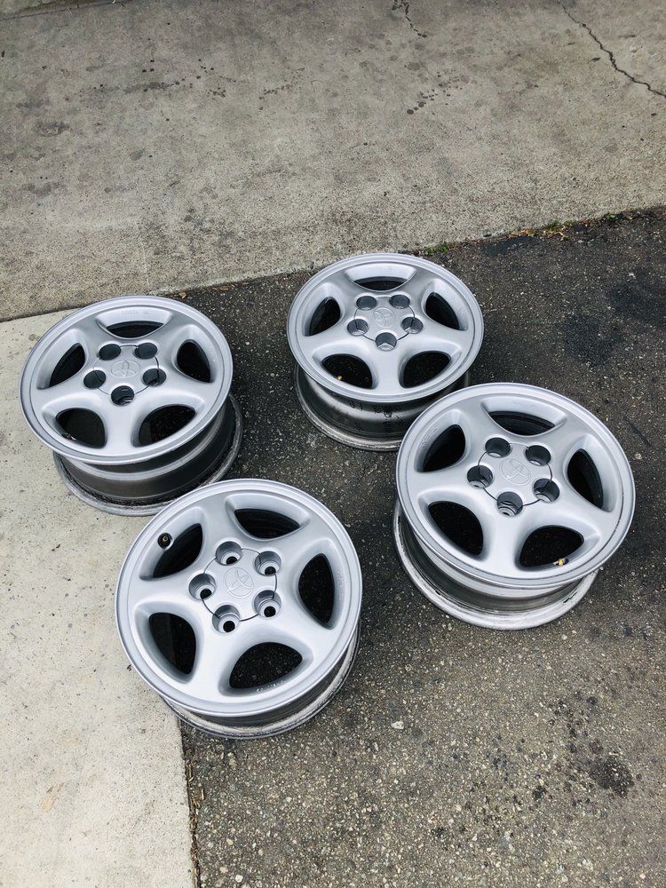 Four silver wheels are sitting on a concrete surface.