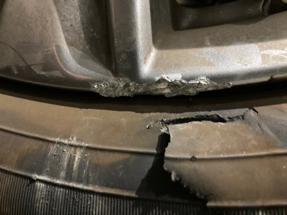 Four silver wheels are sitting on a concrete surface.