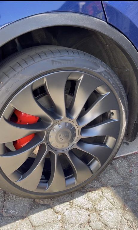 A close up of a tesla wheel with red brake calipers
