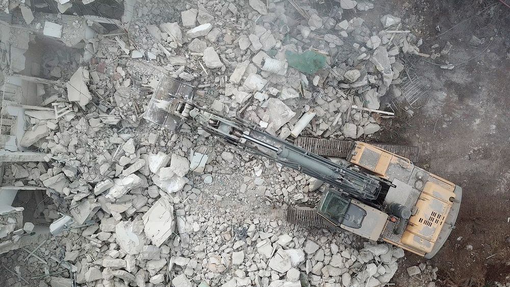 An aerial view of a bulldozer demolishing a building.